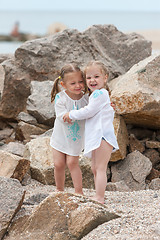 Image showing Children on the sea beach. Twins standing against stones and sea water.