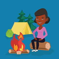 Image showing Woman sitting on log near campfire in the camping.