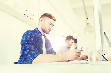 Image showing creative man texting on cellphone at office