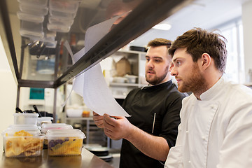 Image showing chef and cook with lists or bills at kitchen