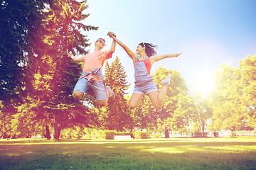 Image showing happy teenage couple jumping at summer park