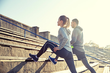 Image showing couple stretching leg on stands of stadium