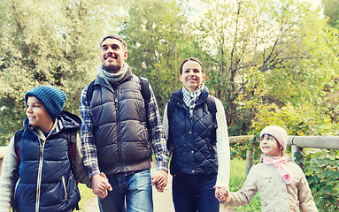 Image showing happy family with backpacks hiking in woods