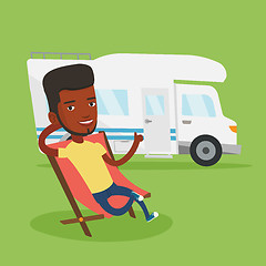 Image showing Man sitting in chair in front of camper van.