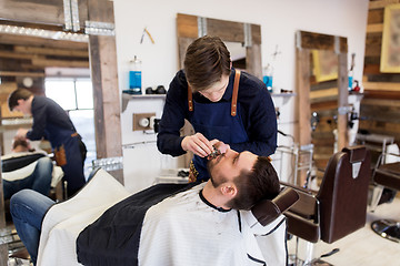 Image showing man and barber with trimmer cutting beard at salon