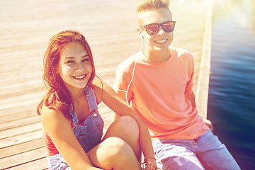 Image showing happy teenage couple with earphones on river berth