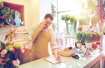 Image showing man with smartphone making notes at flower shop