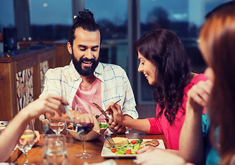 Image showing friends eating and tasting food at restaurant