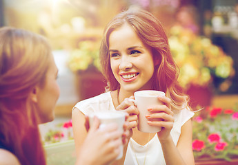 Image showing smiling young women with coffee cups at cafe