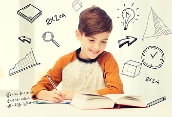 Image showing smiling student boy writing to notebook at home