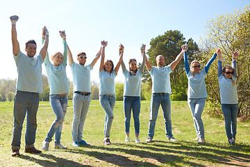 Image showing group of happy volunteers holding hands outdoors