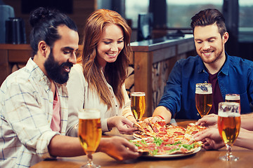 Image showing friends eating pizza with beer at restaurant