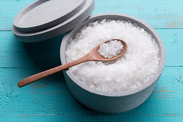 Image showing Sea salt in an stone bowl with small wooden spoon on a blue wooden table