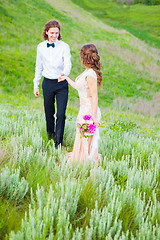 Image showing Just married loving couple in wedding dress on green field in a forest at summer