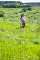 Image showing Just married loving couple in wedding dress on green field in a forest at summer