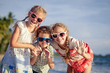 Image showing Three happy children standing on the beach at the day time.