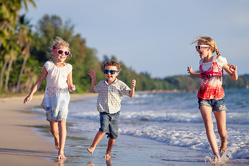 Image showing Three happy children runing on the beach at the day time.