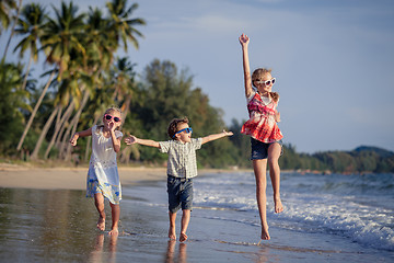 Image showing Three happy children runing on the beach at the day time.