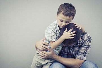 Image showing sad son hugging his dad near wall