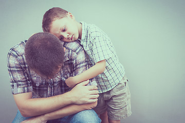 Image showing sad son hugging his dad near wall