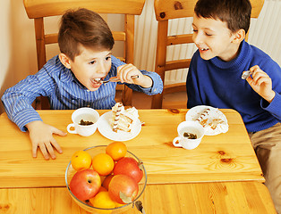 Image showing little cute boys eating dessert on wooden kitchen. home interior