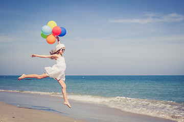 Image showing Teen girl with balloons jumping on the beach