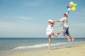 Image showing Father and daughter with balloons playing on the beach at the da