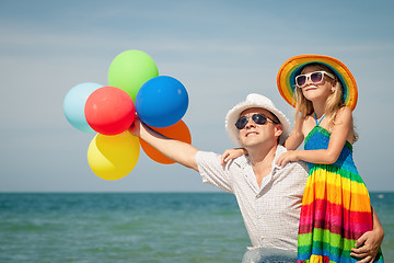 Image showing Father and daughter with balloons playing on the beach at the da