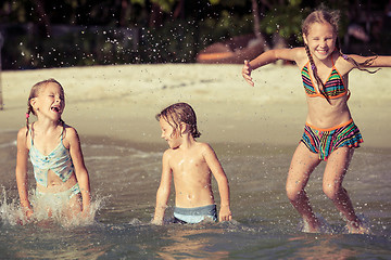 Image showing Three happy children  playing on the beach