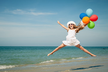 Image showing Teen girl with balloons jumping on the beach