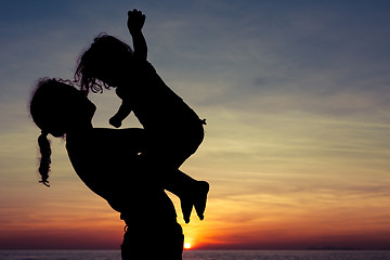 Image showing Mother and son playing on the beach at the sunset time.