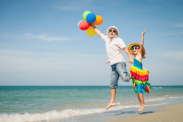 Image showing Father and daughter with balloons playing on the beach at the da