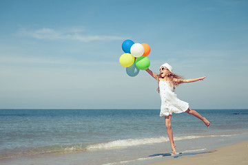 Image showing Teen girl with balloons jumping on the beach