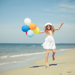 Image showing Teen girl with balloons jumping on the beach