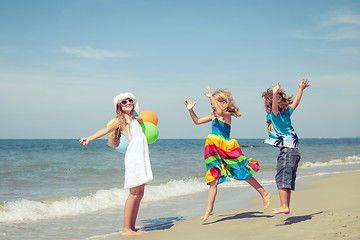 Image showing Three happy children with balloons  dancing on the beach