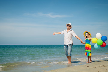 Image showing Father and daughter with balloons playing on the beach at the da