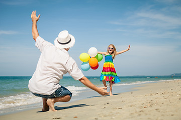 Image showing Father and daughter with balloons playing on the beach at the da