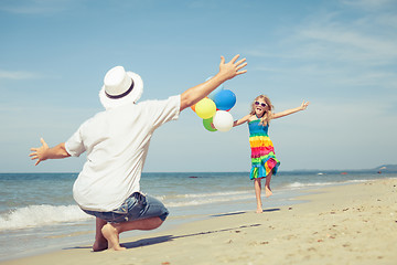 Image showing Father and daughter with balloons playing on the beach at the da