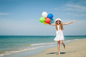 Image showing Teen girl with balloons jumping on the beach