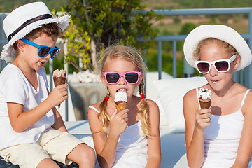 Image showing Three happy children eating ice cream near swimming pool at the 