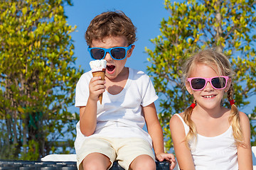 Image showing Three happy children eating ice cream near swimming pool at the 