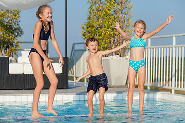 Image showing Three happy children playing on the swimming pool at the day tim