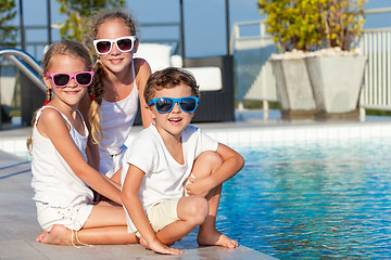 Image showing Three happy children playing on the swimming pool at the day tim