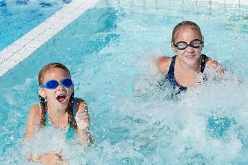 Image showing Two happy children playing on the swimming pool at the day time.