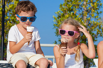 Image showing Three happy children eating ice cream near swimming pool at the 