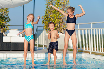 Image showing Three happy children playing on the swimming pool at the day tim