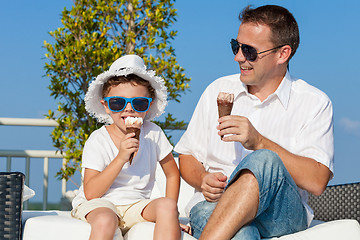 Image showing Father and son relaxing near a swimming pool at the day time.