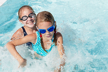 Image showing Two happy children playing on the swimming pool at the day time.