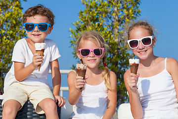 Image showing Three happy children eating ice cream near swimming pool at the 