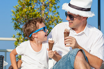 Image showing Father and son relaxing near a swimming pool at the day time. 